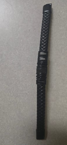 Customer's black braided bracelet with personalized beads lying on a flat grey surface.