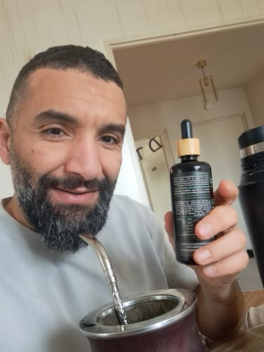 Un client tenant son flacon d'Huile d'algues oméga 3 tout en buvant du maté.