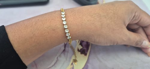 Cliente mostrando la Pulsera Olivia en su muñeca, que tiene un tono dorado antiguo y piedras brillantes.