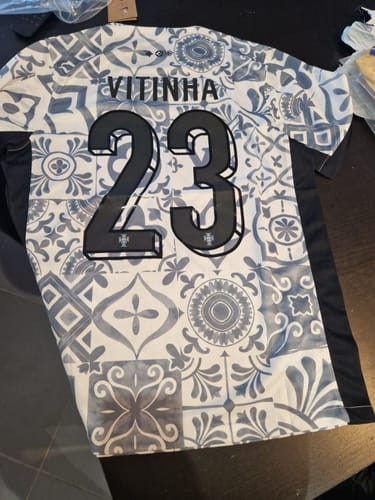 Client montrant le dos du maillot spécial du Portugal, blanc avec un motif à carreaux et le flocage VITINHA 23.