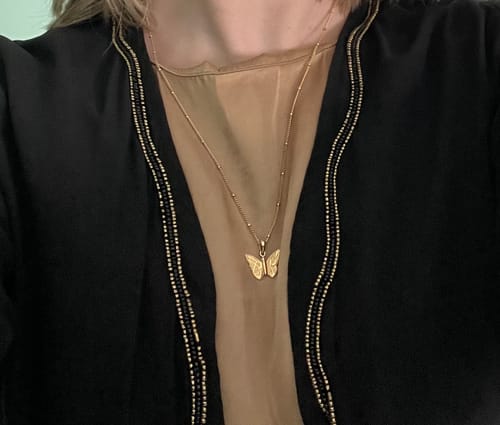 A reviewer wearing the gold Patience & Hope Necklace, showing the butterfly pendant on their chest.