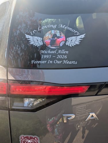 A reviewer's white 'In Loving Memory' decal with a photo and wings applied to a car's rear window.