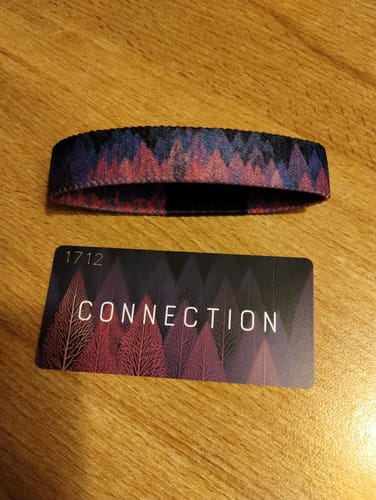 Customer's Connection Bracelet and its front collector card with a purple forest design, displayed on a wooden surface.