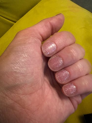 Reviewer's hand showing short nails with a sparkly, pink Rosé Champagne gel manicure.