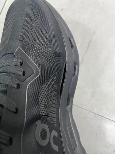 Close-up of a reviewer's black On Cloudzone shoe showing the midsole separating from the upper.