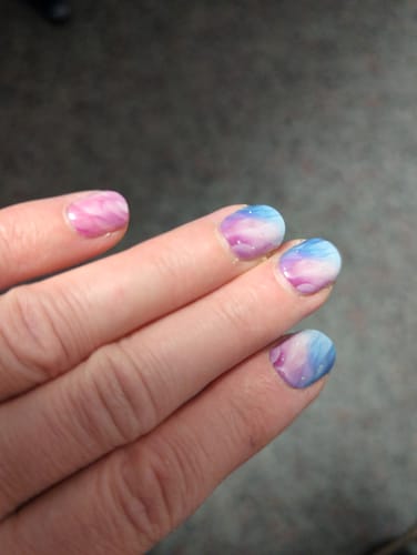 Nahaufnahme der Nägel einer Kundin mit den UV-Gel-Folien 'Pastel Waves' in bunten Pastellfarben.