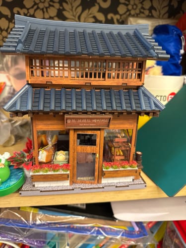 Reviewer's finished Ikseon-dong Hanok Bakery Miniature House Kit, a detailed two-story wooden model with a dark, tiled roof.