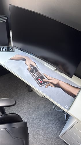 Customer's God Mode mousepad with unique controller art, shown on a clean gaming desk setup with a monitor.