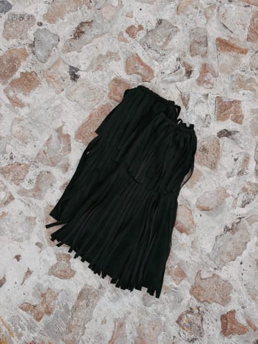 Customer's black, fringed product, possibly a boot accessory, lying on a stone floor.