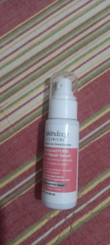 Close-up of the customer's Advanced PDRN Skin Repair Serum bottle on a striped surface.