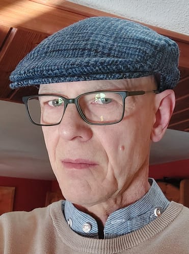 Reviewer in a close-up photo wearing the blue tweed Vintage Cap, showing the fit and texture.