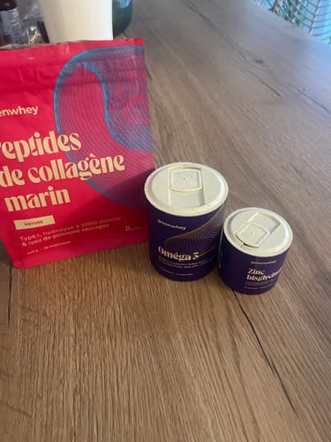Photo d'un client montrant le produit Zinc Bisglycinate à côté des produits Oméga 3 et collagène sur une table en bois.
