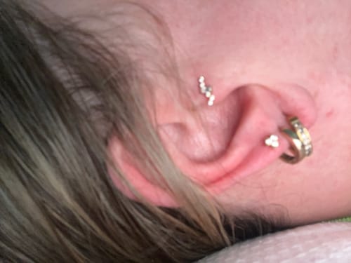 Close-up: Customer's ear showing the Aurora Flatback Stud in a flat piercing, with other earrings visible.
