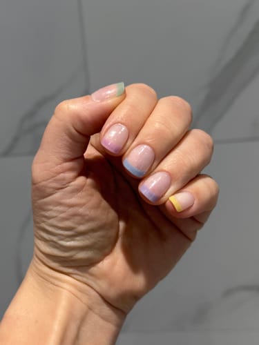 Customer's hand showing a Holy Gels manicure with multicolor pastel French tips.
