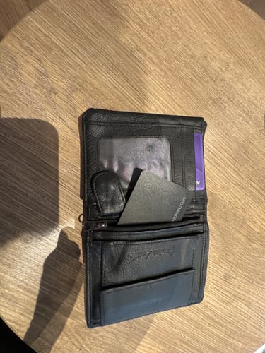 Customer's SPOTMINDERS Tracking Card placed inside a black leather wallet on a wooden table.