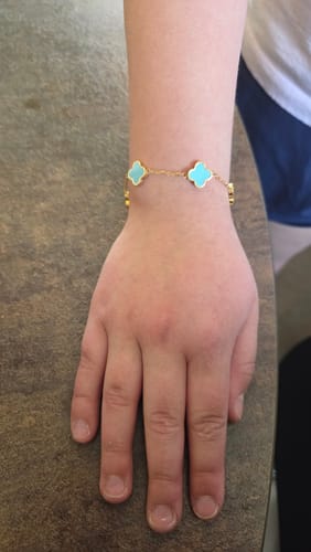 Ein Rezensent trägt das goldene Baby Blue Clover Armband mit hellblauen Kleeblättern am Handgelenk.