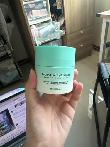 Customer holding the two-toned jar of Cooling Clarity Emulsion in their hand.