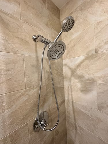 Customer's 1-Spray Handheld Shower Head Set installed on a diverter next to another shower head in a tiled shower.