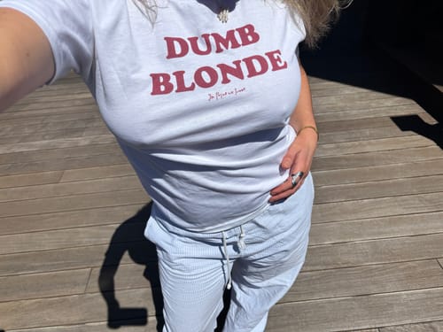 Customer wearing the white Dumb Blonde Baby Tee, showing its relaxed fit outdoors.