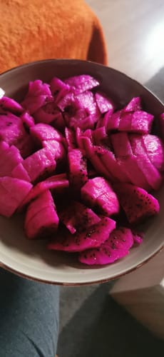 Ein Kunde hält eine Schale mit geschnittener, leuchtend roter Drachenfrucht.