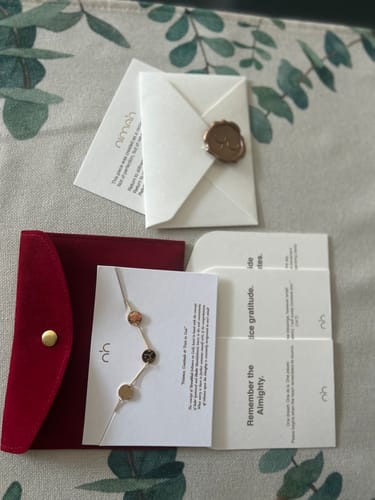 Reviewer's Happiness Bracelet displayed on its card with a red pouch and other elegant packaging elements.