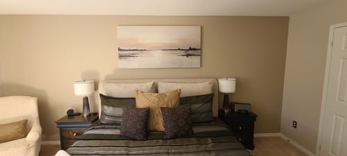 Customer's 'Golden Hour on Lake Ontario' canvas hanging on a bedroom wall above a bed.