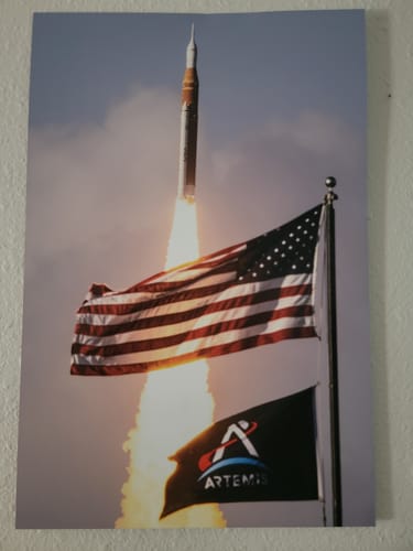 Customer's 'Four Souls, One Rocket' print of the Artemis launch, shown hanging on a wall.
