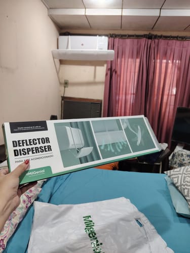 Un cliente sostiene la caja del Deflector Disperser para Aire Acondicionado en una habitación.