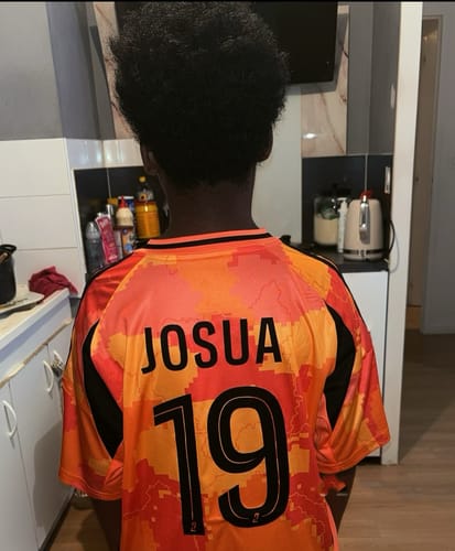 Client vu de dos portant le maillot AJAX Extérieur personnalisé avec 'JOSUA' et le numéro 19.