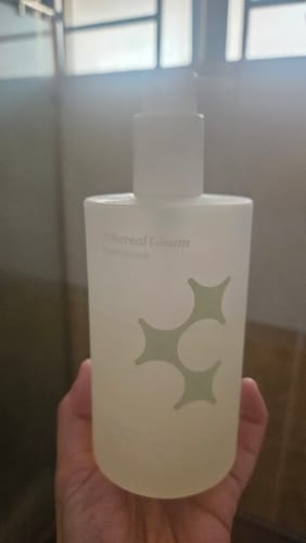 Reviewer holding the frosted pump bottle of Ethereal Gleam Shower Gel in their hand.