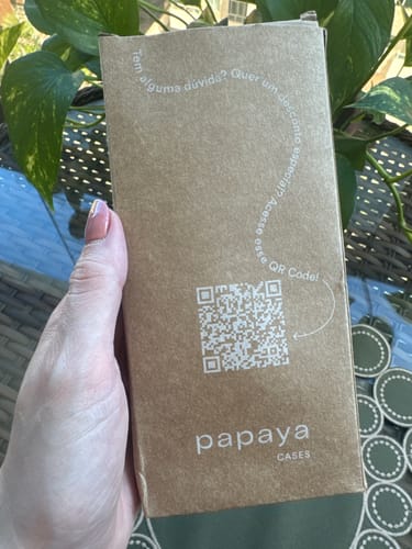 Cliente segurando a embalagem de papelão da Alça Aurora em um ambiente externo.