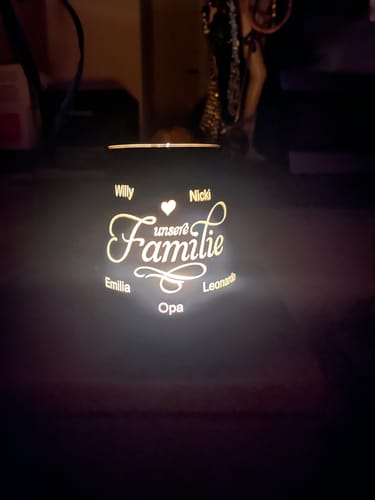 Rezensent zeigt das beleuchtete Deko-Windlicht aus Glas mit der personalisierten Gravur 'Unsere Familie' und Namen.