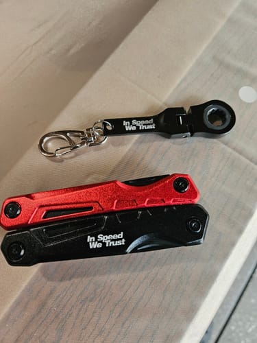 Customer's red and black multi-tool and small ratchet keychain lying on a flat surface.