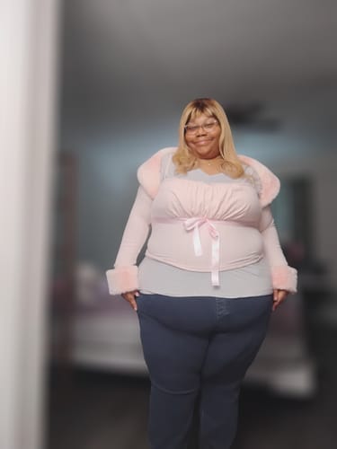 Customer wearing the pink Fawn Fur Bolero Cardigan with fur-trimmed collar and cuffs over a grey top.