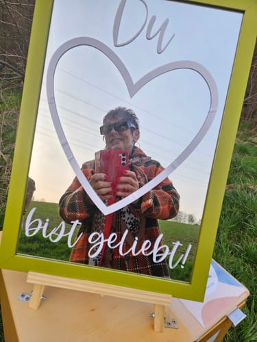 Eine Rezensentin macht ein Selfie in einem dekorativen Spiegel mit der Aufschrift 'Du bist geliebt'.