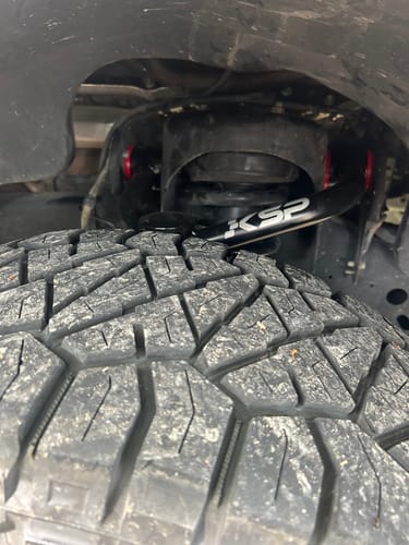 Close-up of a reviewer's new black Upper Control Arm with 'KSP' logo installed above the tire on a Ford F150.