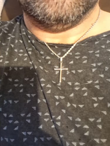 Primer plano de un cliente que lleva una cadena plateada con un colgante de cruz en el cuello.