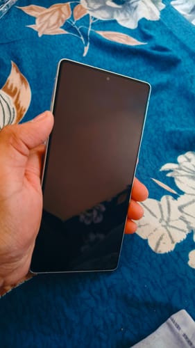Customer holding a smartphone with the UltraShield Tempered Glass applied to the screen against a floral background.