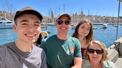 Customer wearing the green Behind The Trees t-shirt in a family photo at a sunny harbor.