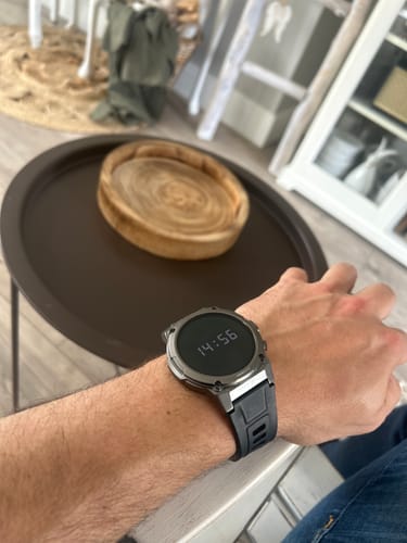 Customer's close-up of a digital watch with a silver case and black strap on their wrist.