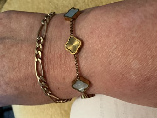 Customer's wrist wearing the Celine Clover Bracelet, showing both the white mother of pearl and textured gold charms.