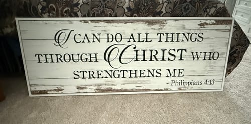 Customer's 'I Can Do All Things...' faith sign with a rustic, white finish leaning against furniture.
