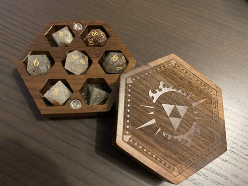 Reviewer's Phantom Quartz dice set in a hexagonal wooden case with its engraved lid resting alongside.