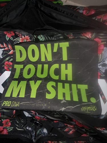 Customer's black Infamous Marker Sleeve with the text "Don't Touch My Shit" in green, sitting on a patterned gear bag.
