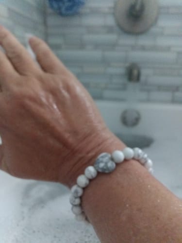 Customer's hand wearing a white and grey beaded crystal bracelet with a heart-shaped stone.