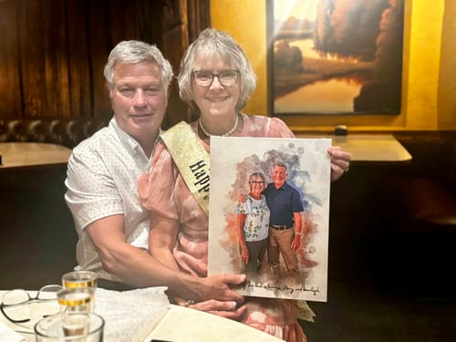 A happy couple holding up their Personalized photo Painting, which features a lovely watercolor-style portrait of them.