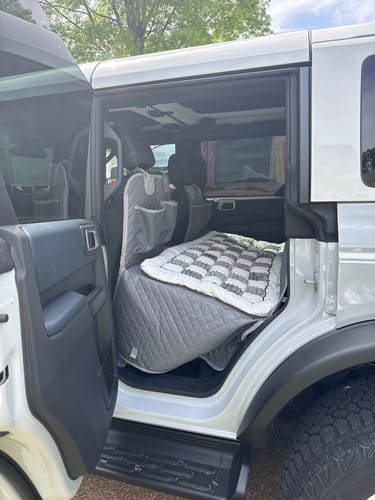 Reviewer's grey, quilted car seat hammock cover installed in the back of an SUV, with a dog bed on top.