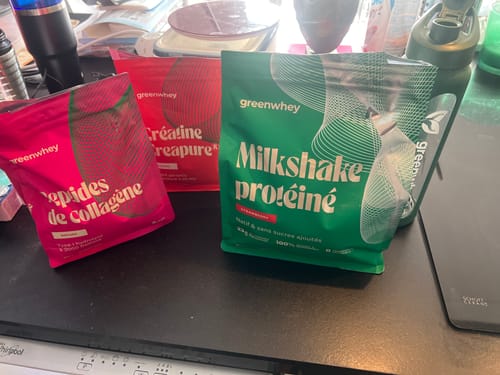 Le Milkshake protéiné d'un client dans son sachet vert, posé sur un comptoir avec d'autres produits.