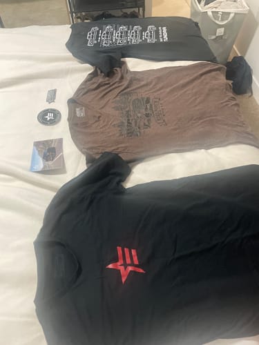 Customer's three graphic t-shirts from their order, including black and brown ones, laid out on a white surface.