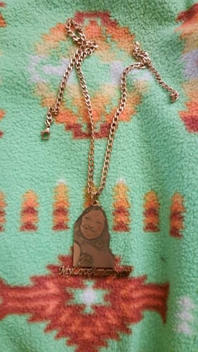 Customer's custom photo engraved pendant necklace showing the front with an engraved portrait of a person.
